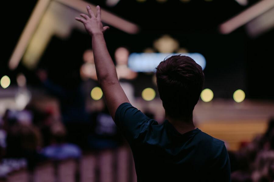 Christian community development minor student raises hand in chapel.